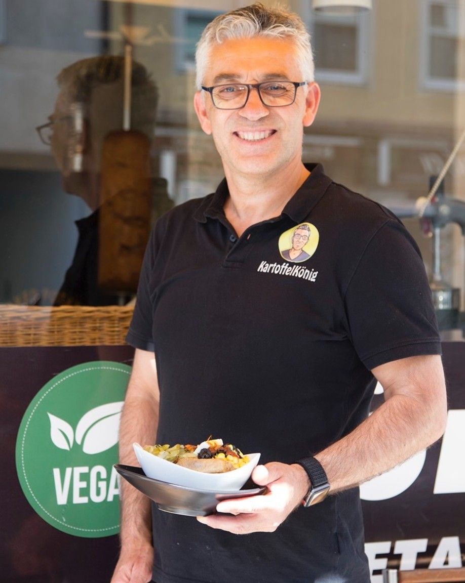 Hüseyin, Gründer vom Kartoffelkönig, mit einer Kumpir vor dem Laden in der Theresienstraße