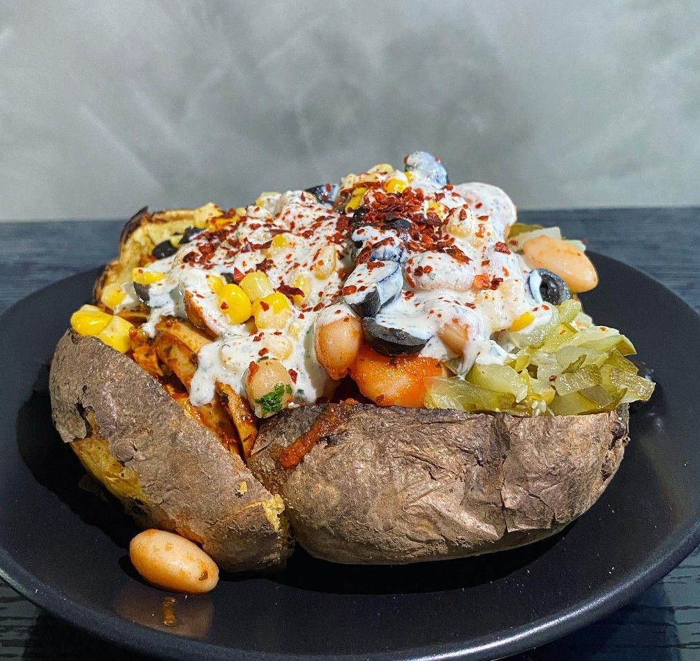 Kumpir mit Bohnen, Mais, Oliven, Joghurtsoße und Chiliflocken