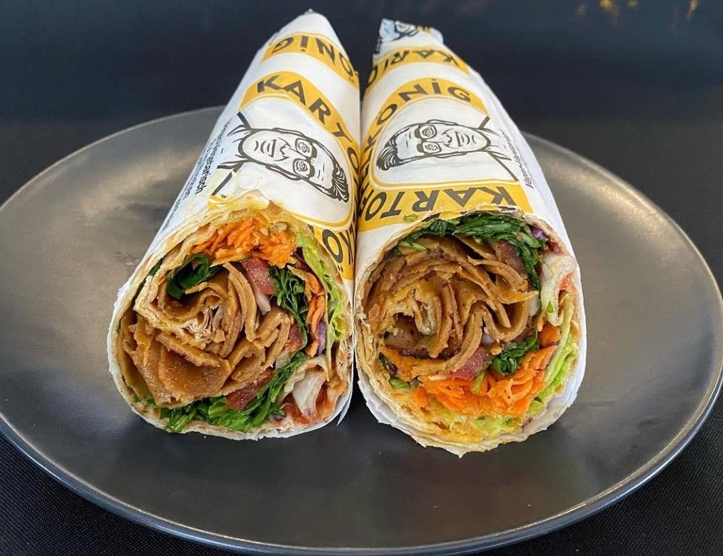Zwei Seitan-Dürüm im Kartoffelkönig-Papier, aufgeschnitten mit Seitan, Salat und Karotten